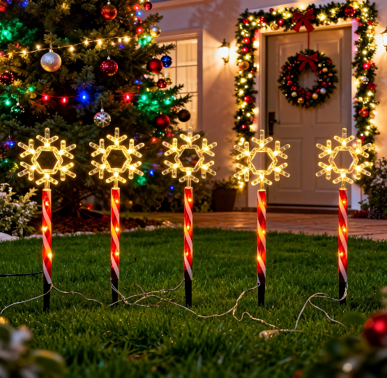 Red tube snowflake stake light with warm white glow in a winter garden - product shot