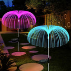 Pink and blue solar jellyfish stake lights beside a garden path